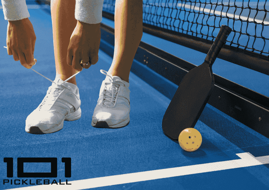 A player tying their shoes on a pickleball court