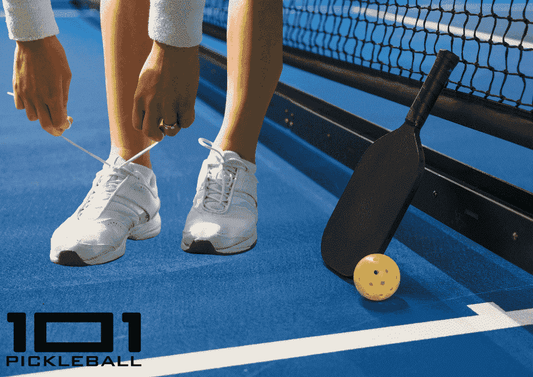 A player tying their shoes on a pickleball court